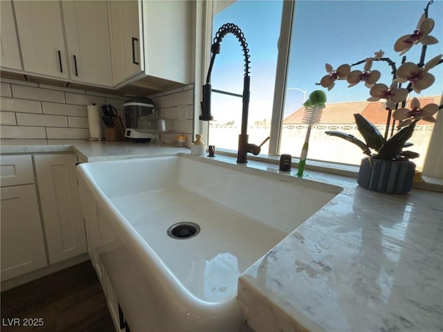 kitchen featuring decorative backsplash, white cabinetry, and sink