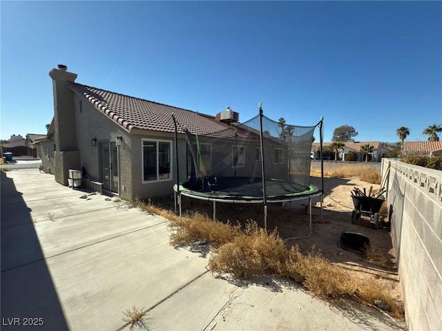 rear view of property with a patio area and a trampoline