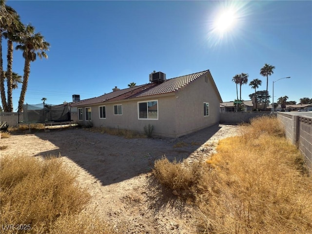 rear view of house with a trampoline and central AC