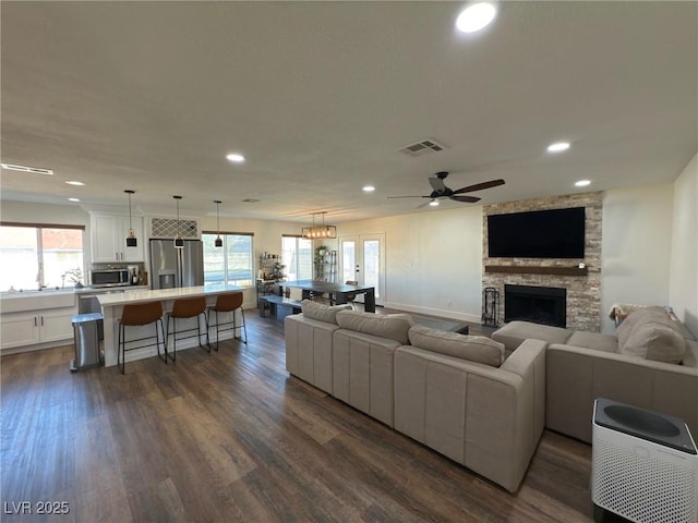 living room with ceiling fan, a fireplace, and dark hardwood / wood-style floors