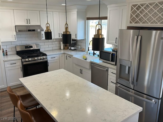 kitchen with tasteful backsplash, stainless steel appliances, sink, white cabinetry, and hanging light fixtures