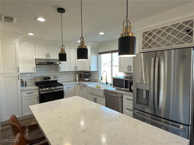 kitchen with light stone counters, sink, white cabinets, and stainless steel appliances