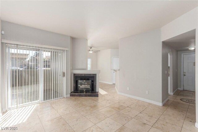 unfurnished living room featuring a tiled fireplace, ceiling fan, and light tile patterned floors