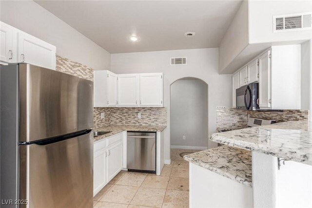 kitchen with light stone countertops, light tile patterned floors, decorative backsplash, white cabinetry, and appliances with stainless steel finishes