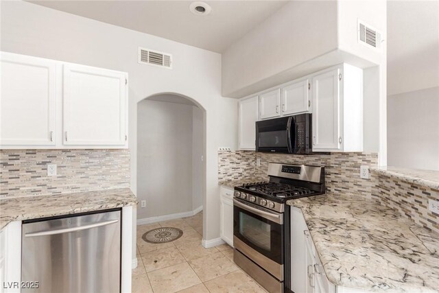 kitchen featuring light stone countertops, stainless steel appliances, light tile patterned floors, tasteful backsplash, and white cabinetry