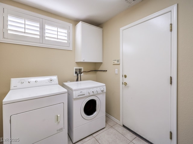 washroom featuring separate washer and dryer, cabinets, and light tile patterned floors