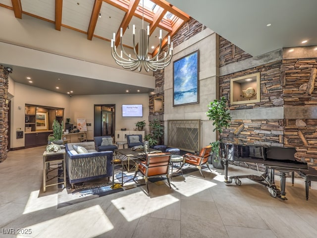 living room featuring a large fireplace, a skylight, beamed ceiling, high vaulted ceiling, and an inviting chandelier