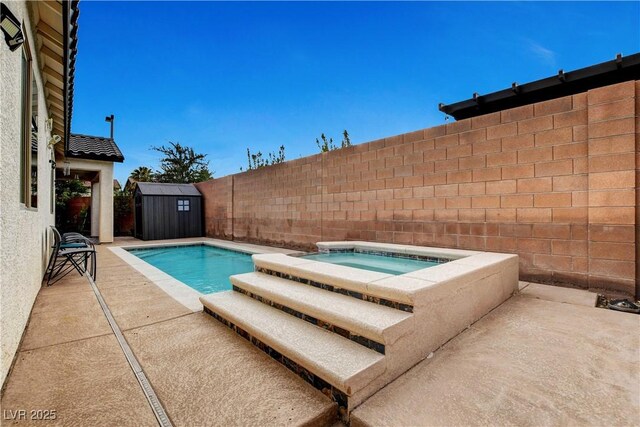 view of pool with a patio, an in ground hot tub, and a shed