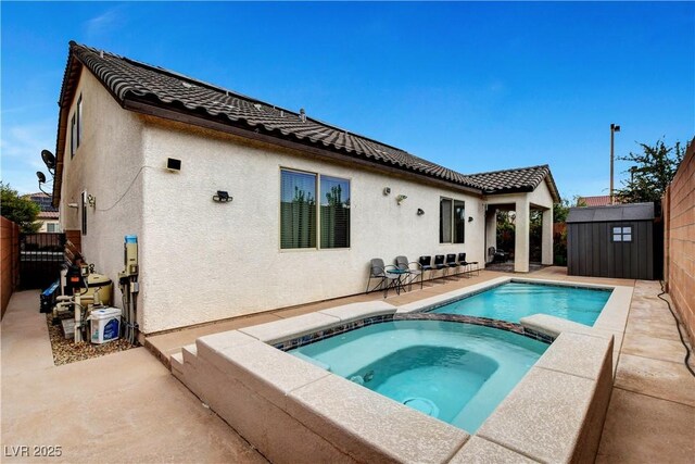 rear view of house featuring an in ground hot tub, a storage shed, and a patio