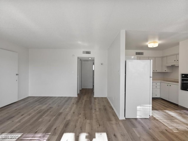 kitchen featuring light hardwood / wood-style flooring, white refrigerator, white cabinetry, and oven