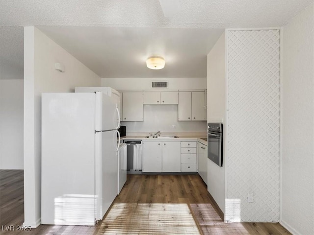 kitchen featuring appliances with stainless steel finishes, dark hardwood / wood-style flooring, white cabinetry, and sink