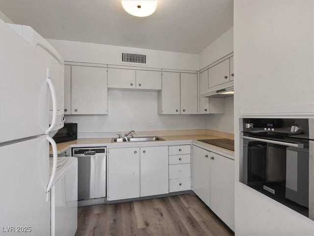 kitchen with white cabinets, black appliances, dark hardwood / wood-style flooring, and sink