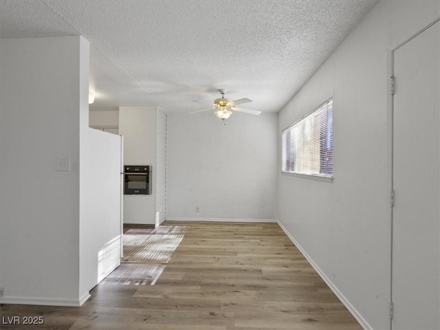 interior space with light wood-type flooring, ceiling fan, and a textured ceiling