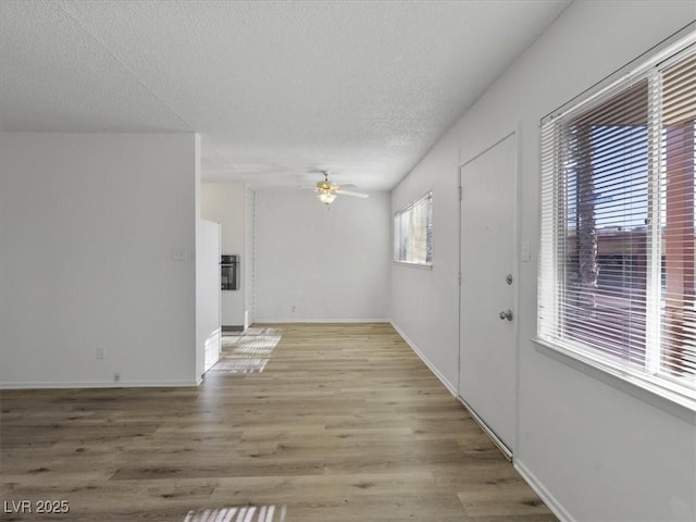 interior space with a textured ceiling, ceiling fan, and light hardwood / wood-style floors