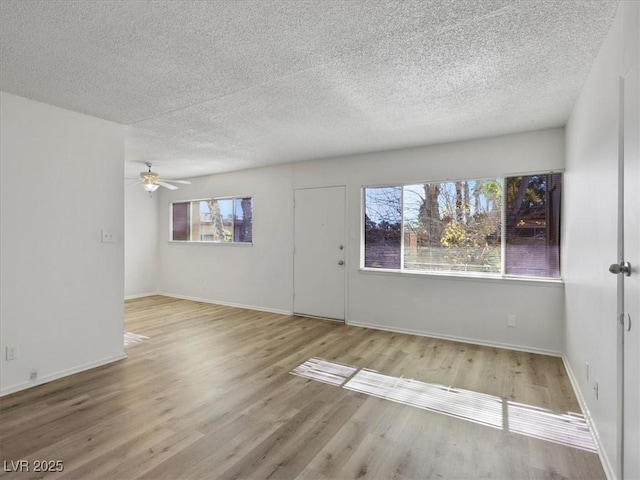 unfurnished room with a textured ceiling, ceiling fan, light hardwood / wood-style floors, and a healthy amount of sunlight