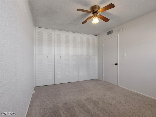 unfurnished bedroom featuring a closet, a textured ceiling, ceiling fan, and carpet flooring