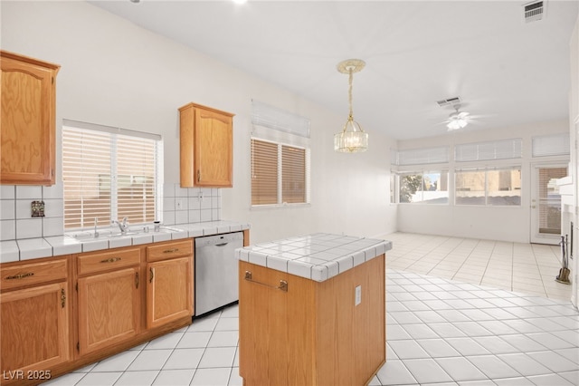 kitchen with light tile patterned flooring, ceiling fan, stainless steel dishwasher, tile counters, and backsplash