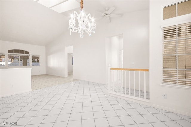 tiled empty room featuring lofted ceiling and ceiling fan with notable chandelier