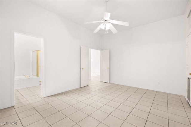 empty room featuring a towering ceiling, light tile patterned flooring, and ceiling fan