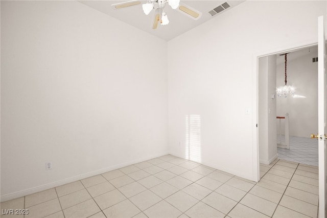 tiled empty room featuring ceiling fan with notable chandelier