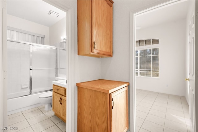 full bathroom featuring toilet, tile patterned floors, vanity, and enclosed tub / shower combo