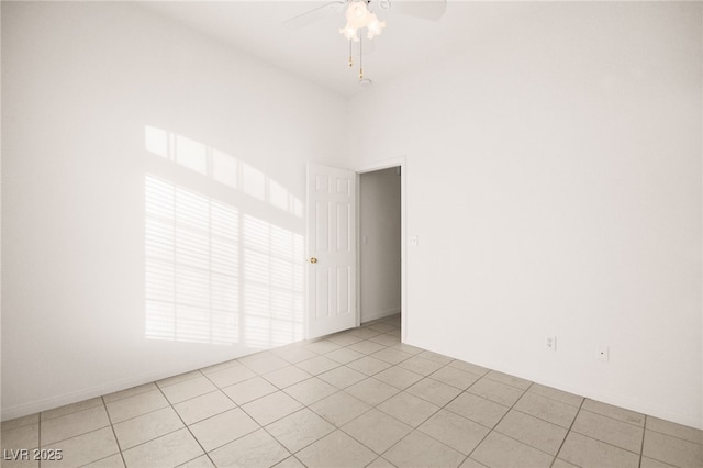 empty room with a towering ceiling, light tile patterned flooring, and ceiling fan