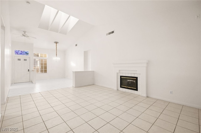 unfurnished living room featuring ceiling fan with notable chandelier, a tile fireplace, high vaulted ceiling, and light tile patterned floors