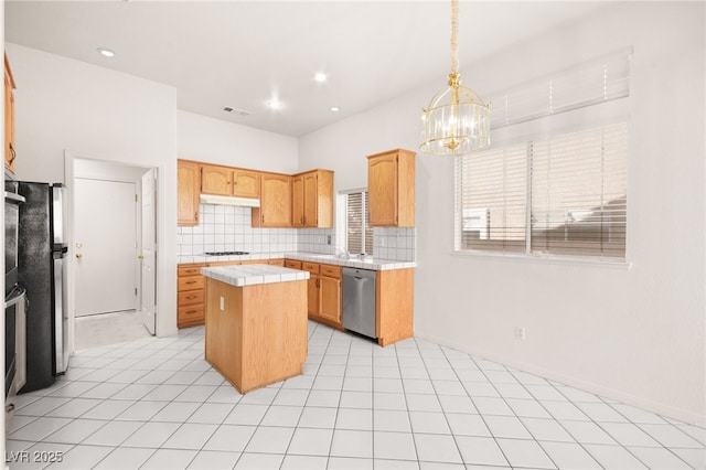 kitchen with a center island, pendant lighting, fridge, stainless steel dishwasher, and backsplash