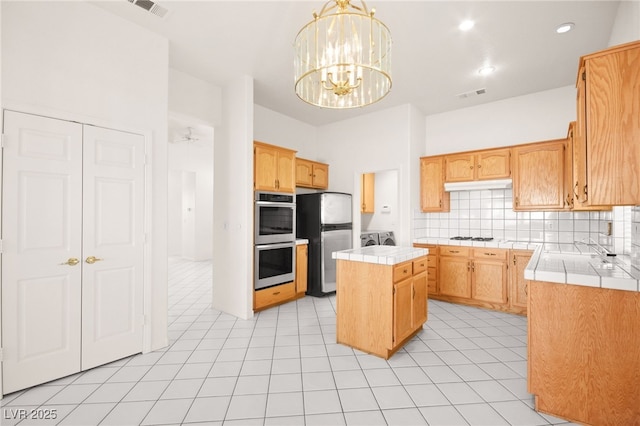 kitchen featuring stainless steel appliances, a center island, a notable chandelier, pendant lighting, and tasteful backsplash