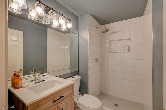 bathroom with toilet, a tile shower, and vanity