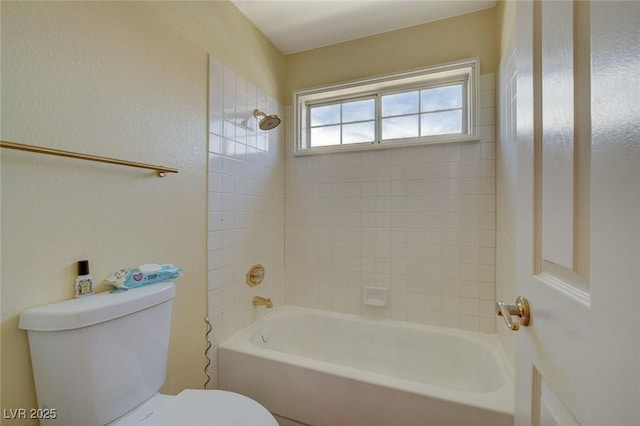 bathroom with toilet and tiled shower / bath