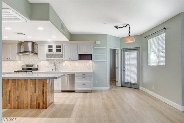 kitchen featuring stainless steel appliances, sink, decorative light fixtures, wall chimney exhaust hood, and decorative backsplash