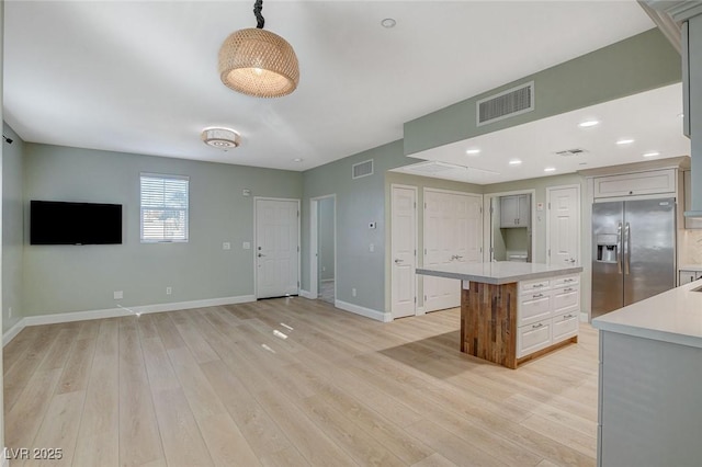 kitchen with gray cabinetry, light wood-type flooring, pendant lighting, a kitchen island, and stainless steel refrigerator with ice dispenser