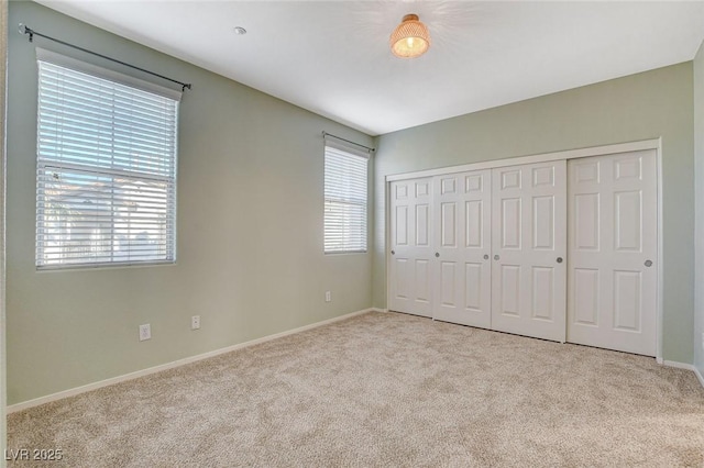 unfurnished bedroom with light colored carpet, a closet, and multiple windows