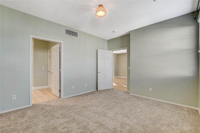 unfurnished bedroom featuring light colored carpet and connected bathroom