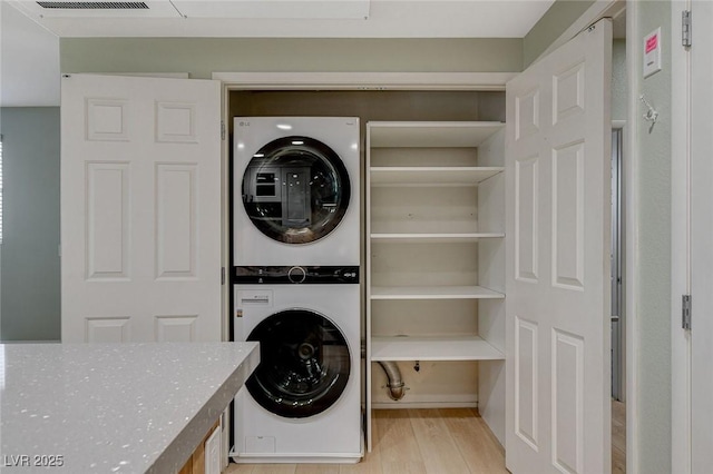 laundry area featuring light hardwood / wood-style flooring and stacked washer and dryer