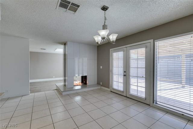 interior space featuring a textured ceiling, a chandelier, french doors, a multi sided fireplace, and light tile patterned flooring