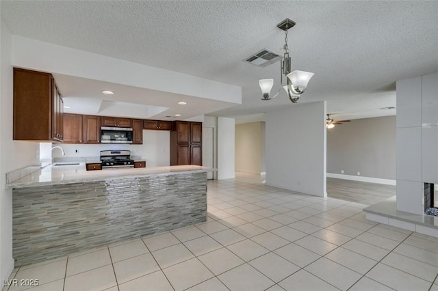 kitchen featuring appliances with stainless steel finishes, hanging light fixtures, kitchen peninsula, light tile patterned floors, and sink