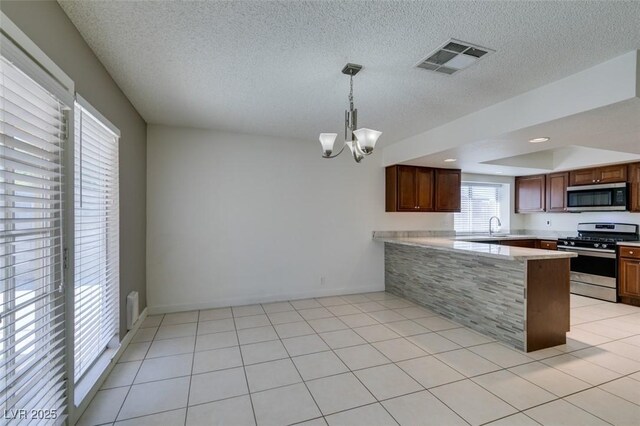 kitchen with appliances with stainless steel finishes, hanging light fixtures, kitchen peninsula, sink, and an inviting chandelier