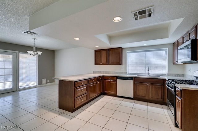 kitchen with appliances with stainless steel finishes, hanging light fixtures, kitchen peninsula, sink, and an inviting chandelier