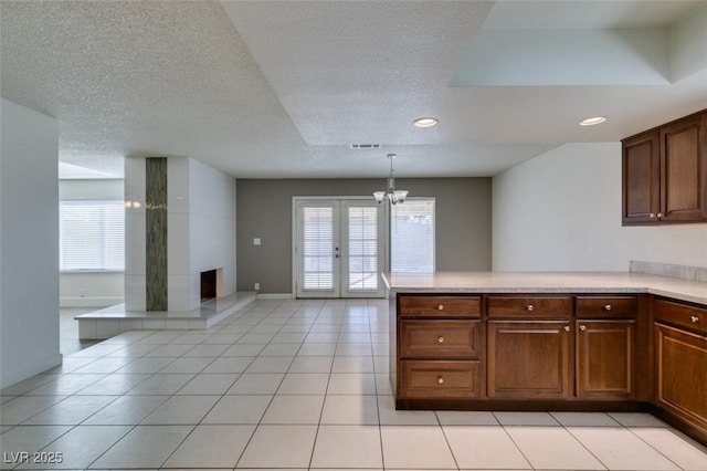 kitchen featuring kitchen peninsula, pendant lighting, a notable chandelier, french doors, and light tile patterned floors