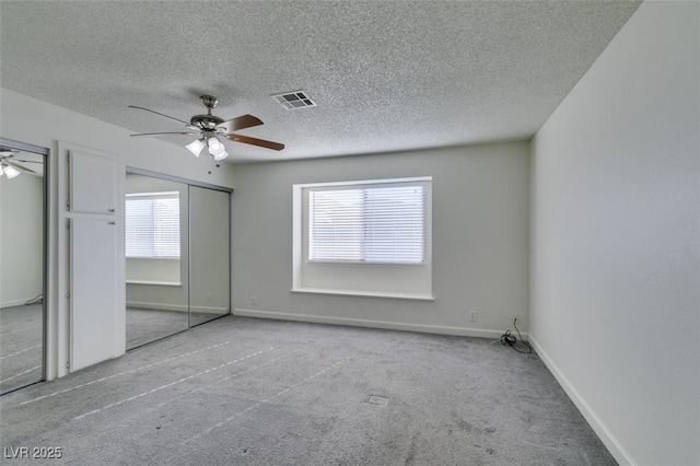 unfurnished bedroom with a textured ceiling, ceiling fan, and light carpet