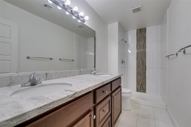 bathroom featuring toilet, tiled shower, tile patterned floors, and vanity