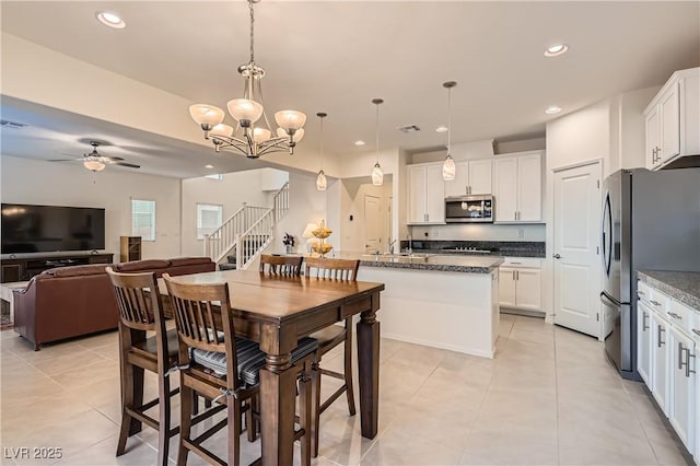 dining space with ceiling fan with notable chandelier and light tile patterned floors