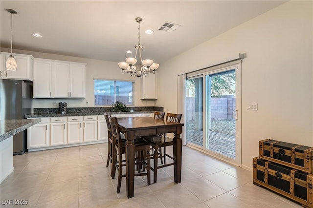 kitchen featuring decorative light fixtures, an inviting chandelier, stainless steel refrigerator, and white cabinets