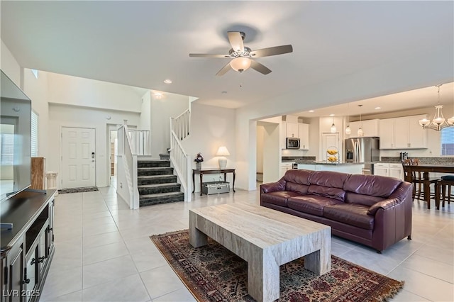 living room featuring ceiling fan with notable chandelier and light tile patterned floors