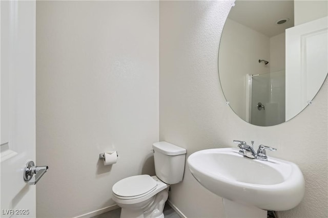 bathroom with sink, a shower with shower door, and toilet