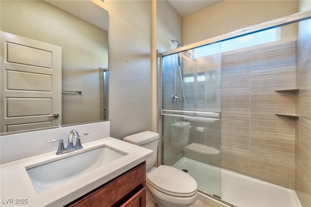 bathroom featuring toilet, a shower with door, and vanity