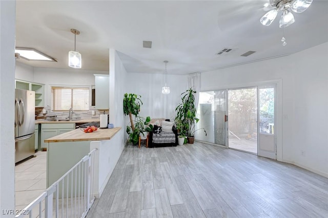 kitchen featuring tasteful backsplash, kitchen peninsula, wooden counters, stainless steel refrigerator, and a wealth of natural light