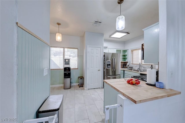 kitchen featuring stainless steel fridge with ice dispenser, decorative light fixtures, wood counters, and kitchen peninsula